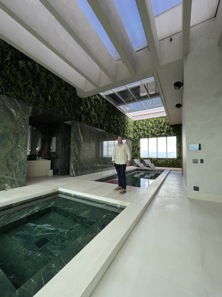 Vista vertical da área de piscina e spa da Cobertura LFP com a parede verde e o pé-direito duplo