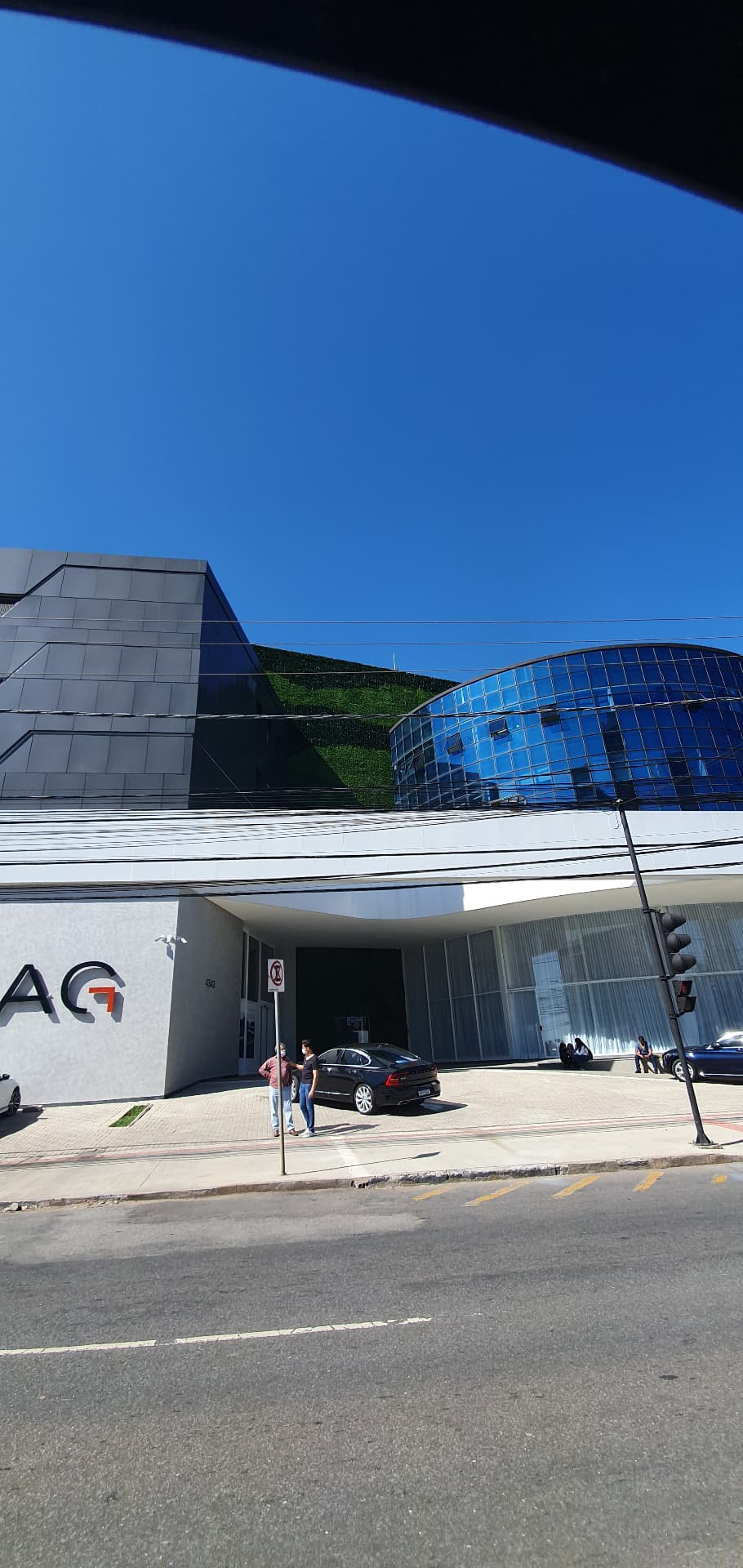 Fachada da Avantgarde Motors vista do outro lado da avenida, com o jardim vertical permanente acompanhando a empena do prédio