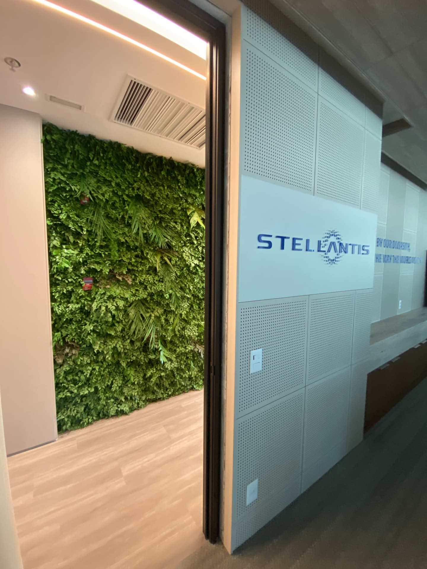 Jardim vertical preservado ao lado do letreiro Stellantis na recepção do escritório