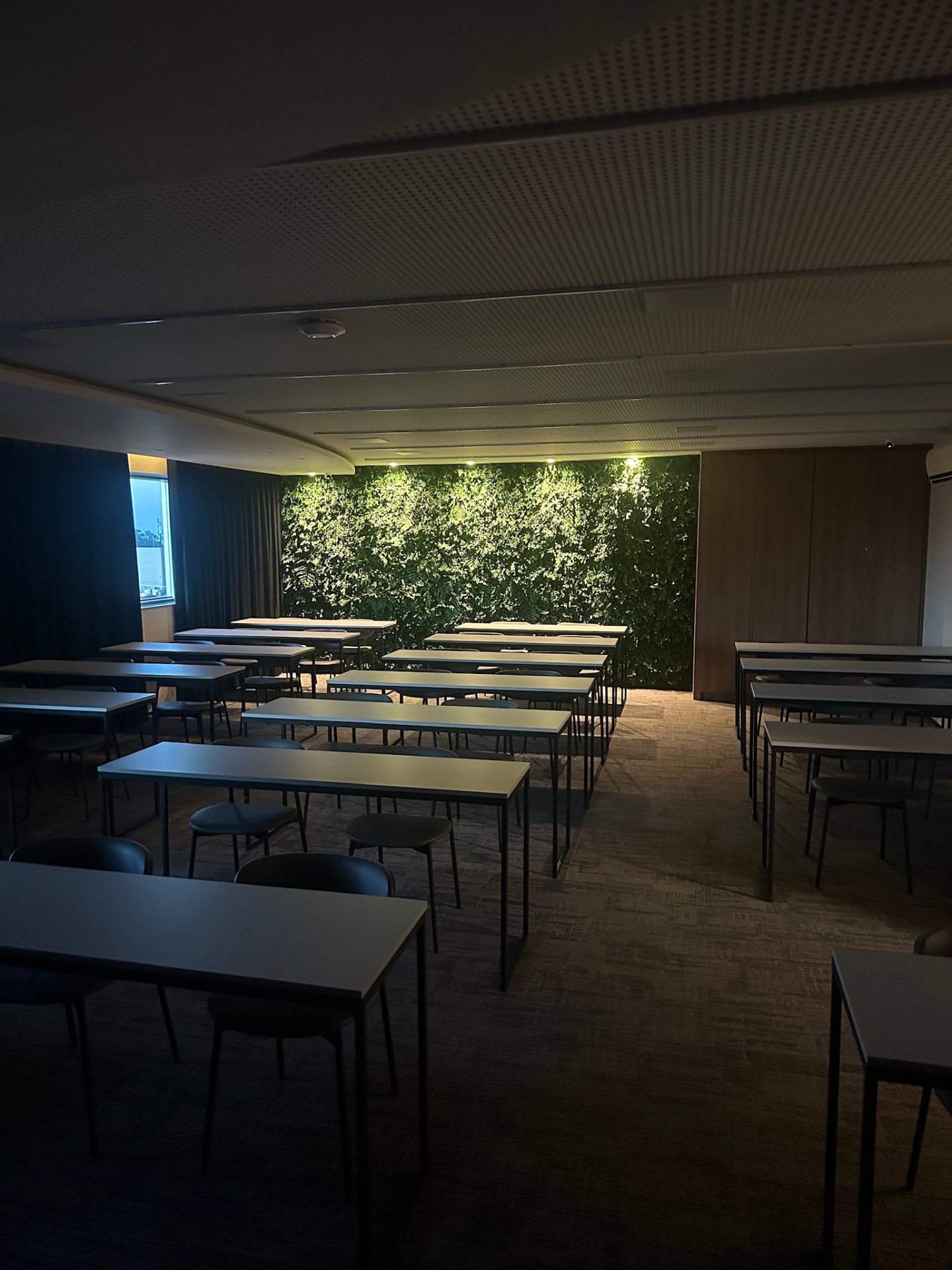 Auditório de treinamentos da ML2 Company com jardim vertical preservado iluminado ao fundo
