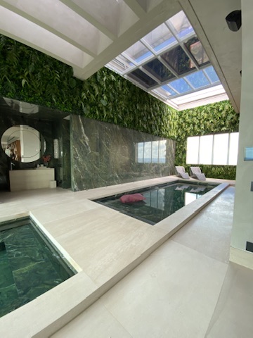 Vista da piscina e do spa da Cobertura LFP com mármore verde e parede verde ao fundo