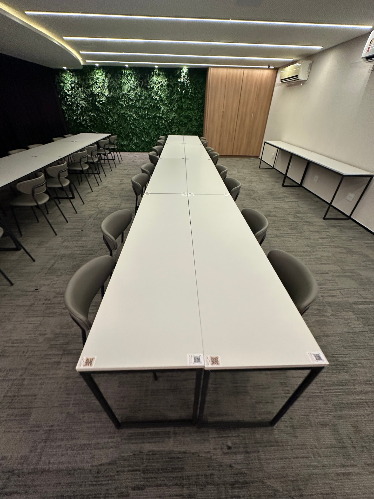 Sala de treinamento da ML2 Company com mesas longas e jardim vertical preservado