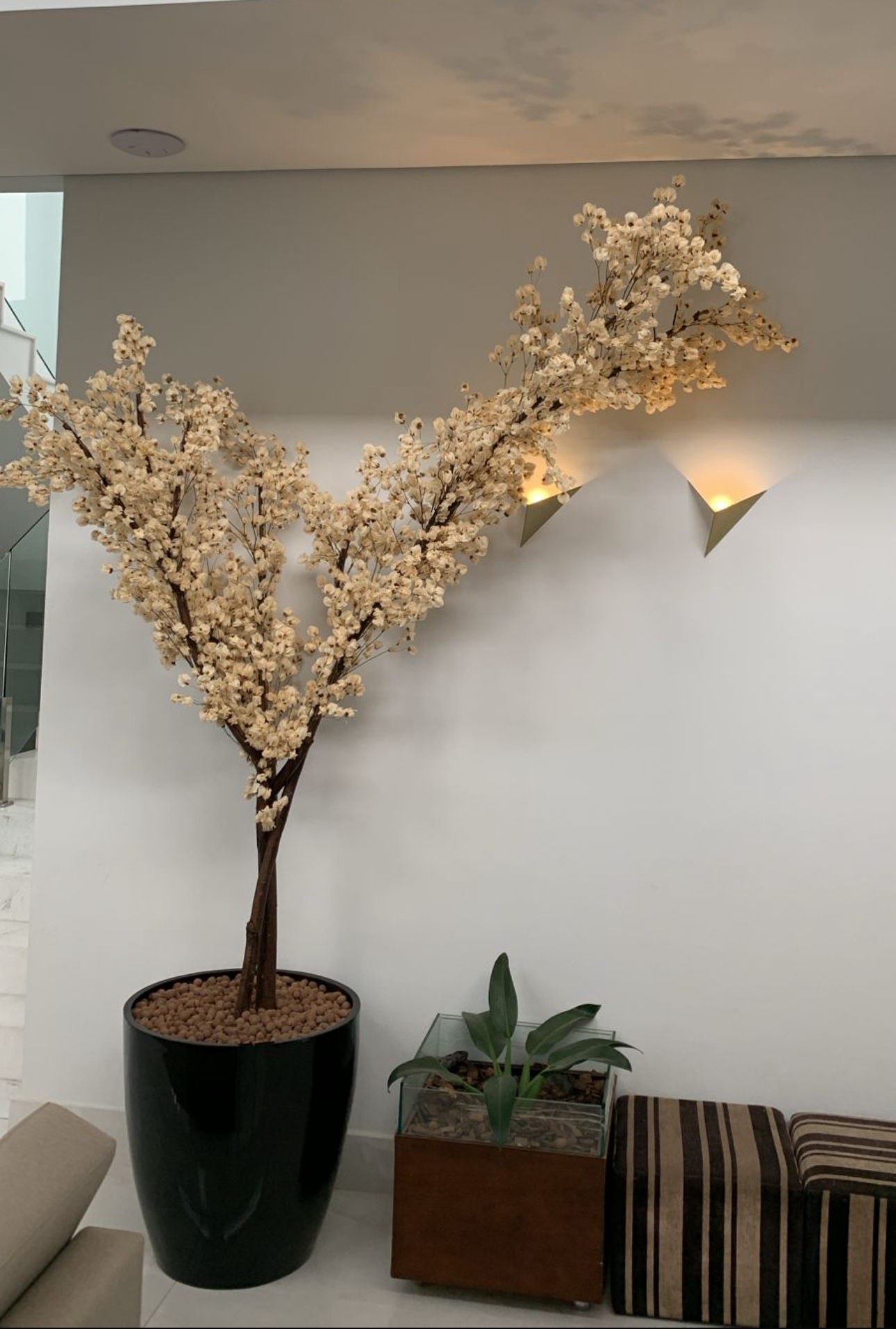 Bougainville champanhe de grande porte em vaso preto em living com escada de vidro