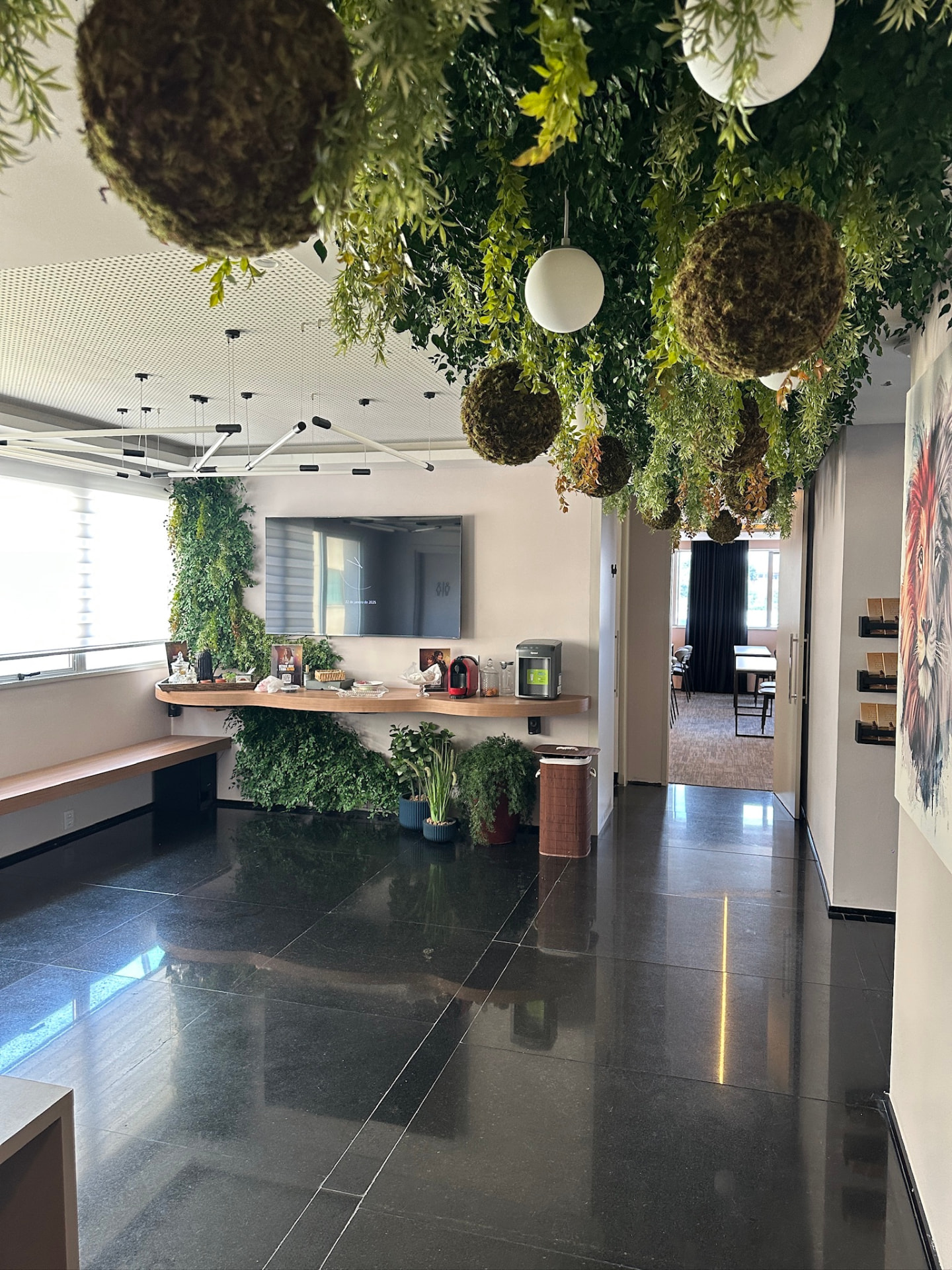 Recepção da ML2 Company com teto preservado, bolas de musgo, luminárias globulares e painel verde