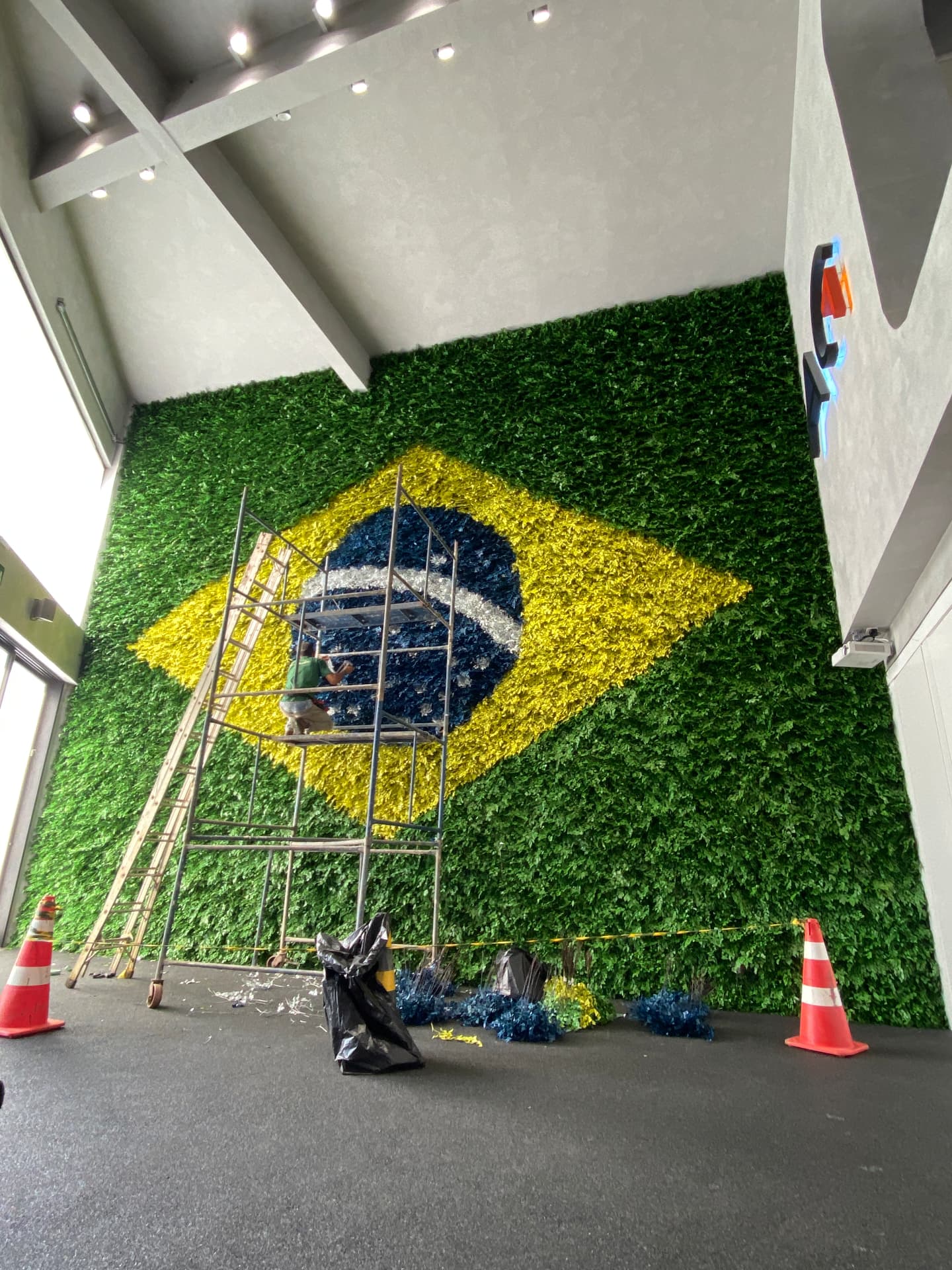 Jardineiro grampeando à mão as folhas azuis do círculo da bandeira em andaime
