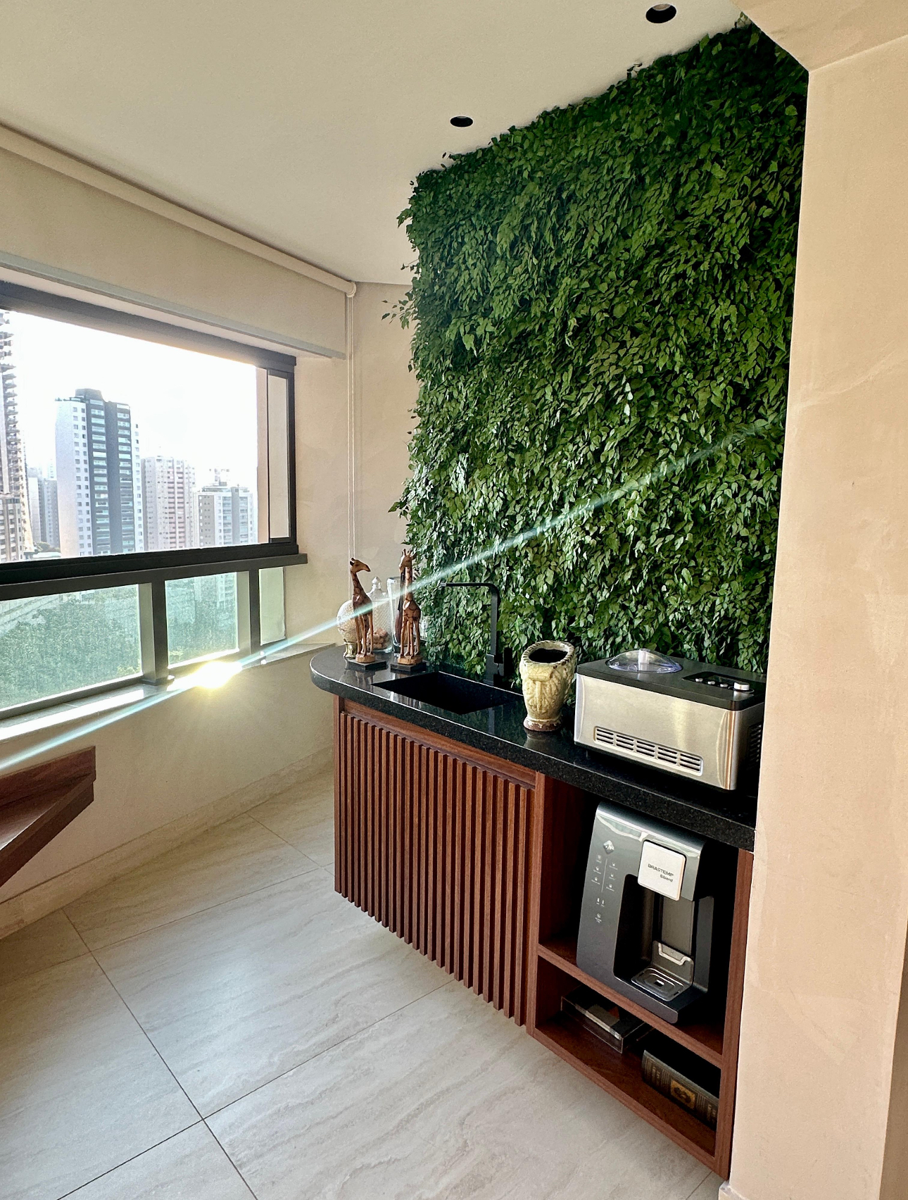 Jardim vertical preservado sobre bancada de granito em varanda gourmet de apartamento