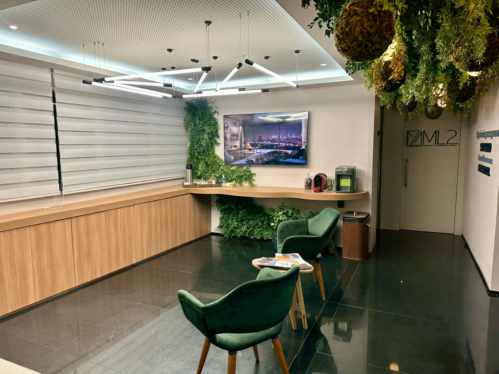 Vista ampla do lounge da ML2 Company com painel preservado, bancada, poltronas e teto vegetal