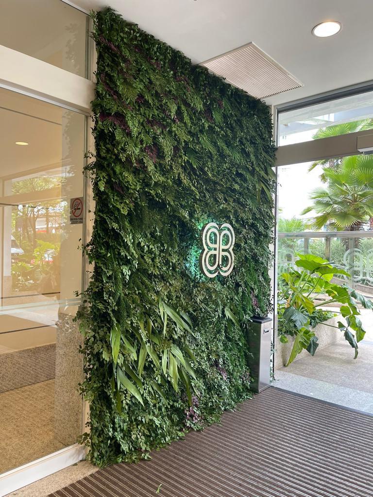 Jardim vertical preservado em recepção corporativa em Belo Horizonte, com logo iluminada sobre o painel verde