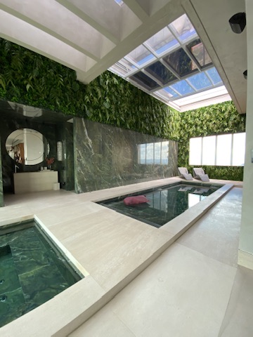 Área de piscina da Cobertura LFP no Belvedere, em Belo Horizonte, com parede verde de fundo permanente e folhas preservadas executada pela Casa do Jardim