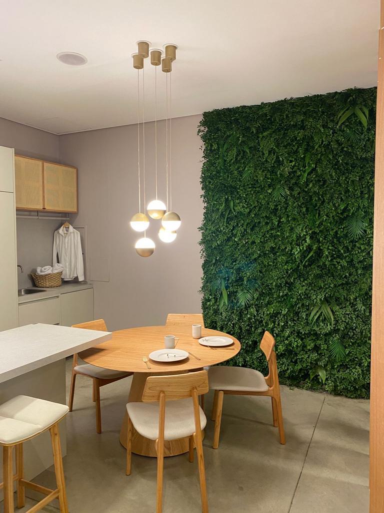 Jardim vertical preservado em área de jantar residencial com pendentes e mesa de madeira