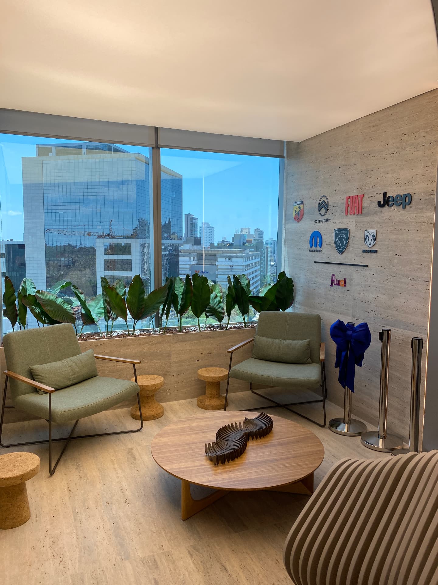 Poltronas do lounge da Stellantis com jardineira de bananeiras junto à fachada de vidro