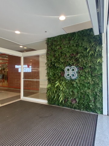 Vista frontal do painel preservado do Acesso A do BH Shopping, com folhagens verdes e bordô e marca central