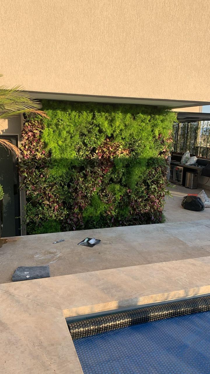 Jardim vertical natural em área gourmet de cobertura com plantas verdes e roxas